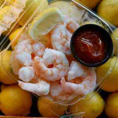 Pink key west shrimp cocktail platter with lemon and seafood sauce.