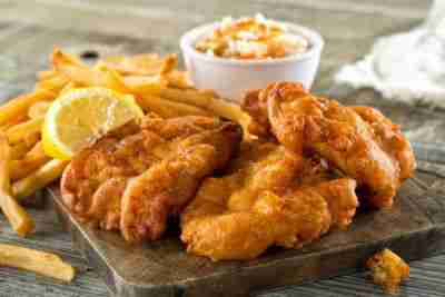 Delicious homemade fish and chips with coleslaw and lemon garnish.