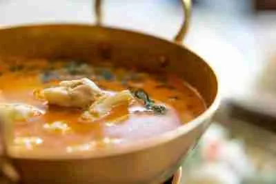 Crab curry with betel leaves in a brass pan.