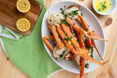 Wide view of steamed crab legs with garlic butter, lemon, and parsley flakes