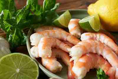 Shrimps with lime and herbs on wooden table, closeup