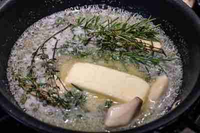 Melted herb butter with garlic read to be poured on a stone crab